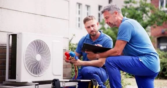 Two HVAC technicians evaluating an outdoor home comfort system