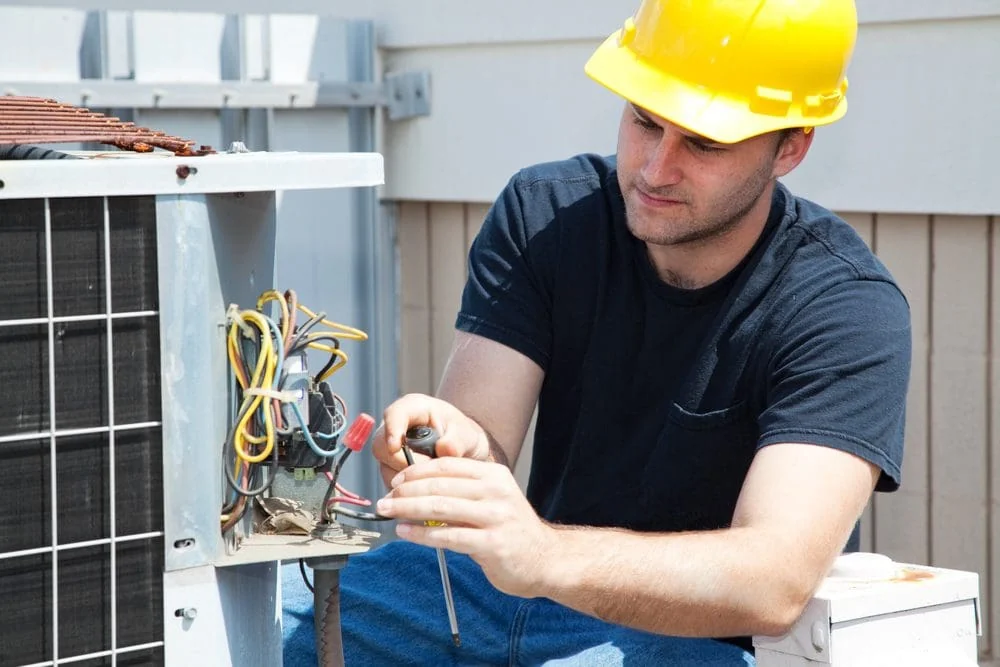 HVAC technician testing an outdoor residential air conditioning unit