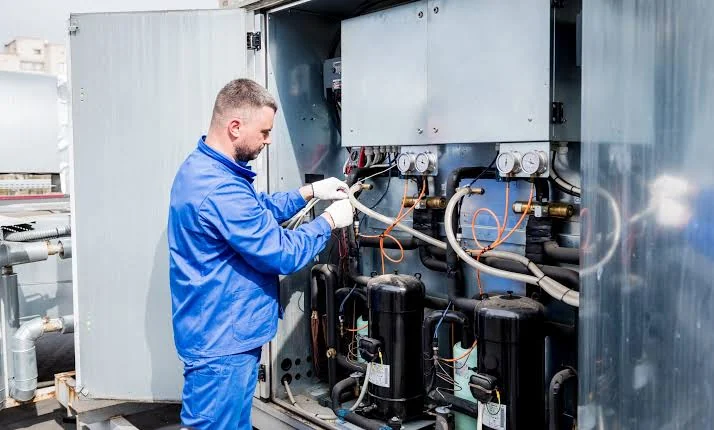 HVAC technician checking gauges and components in a large cooling system