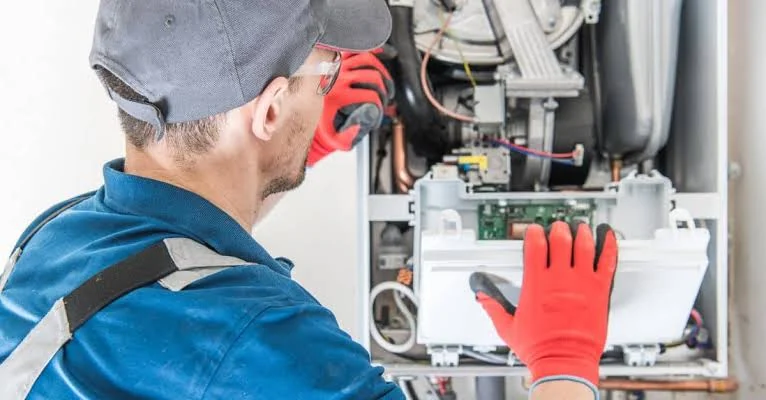Technician examining internal controls in a heating system cabinet