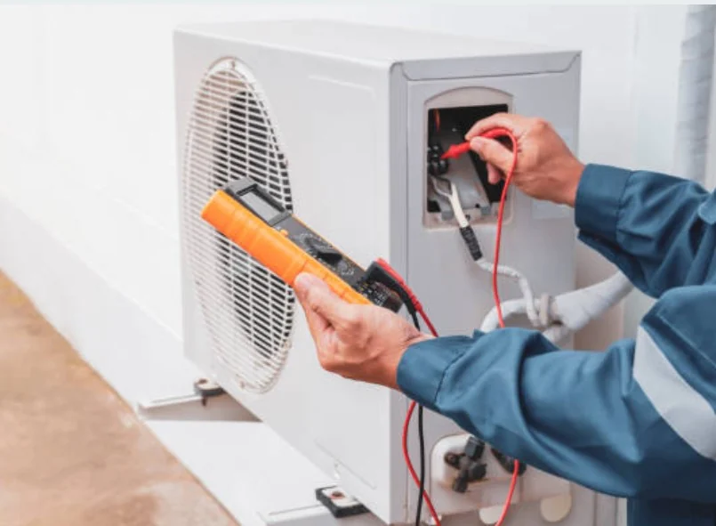 Technician testing an outdoor air conditioning condenser with a multimeter